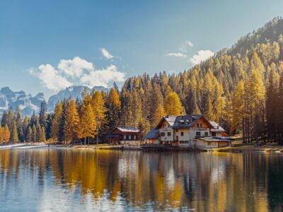 wooden cabin situated right on the lake with autumn-colored trees in the background