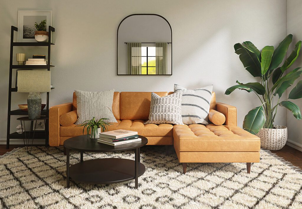 A well decorated vacation rental living room space with a bookcase, wall art mirror, rug, and large plant surrounding a tan leather sofa.